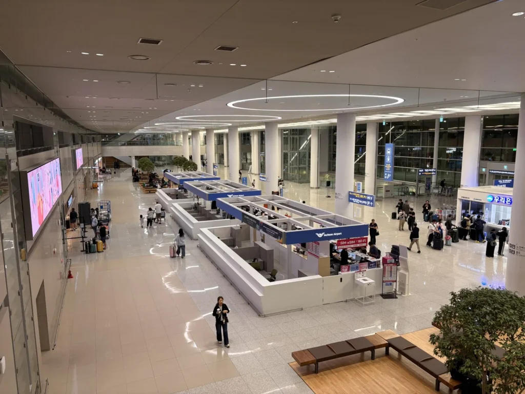 仁川空港第2ターミナルの到着ロビーにあるサービス窓口と旅行者。