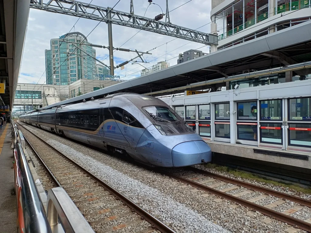 A blue and silver KTX-Cheongryong train passing a platform at Digital Media City station.